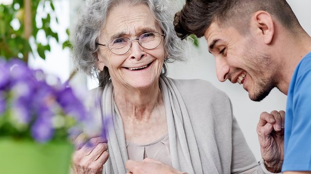 Pflegefachkraft und Seniorin lachend