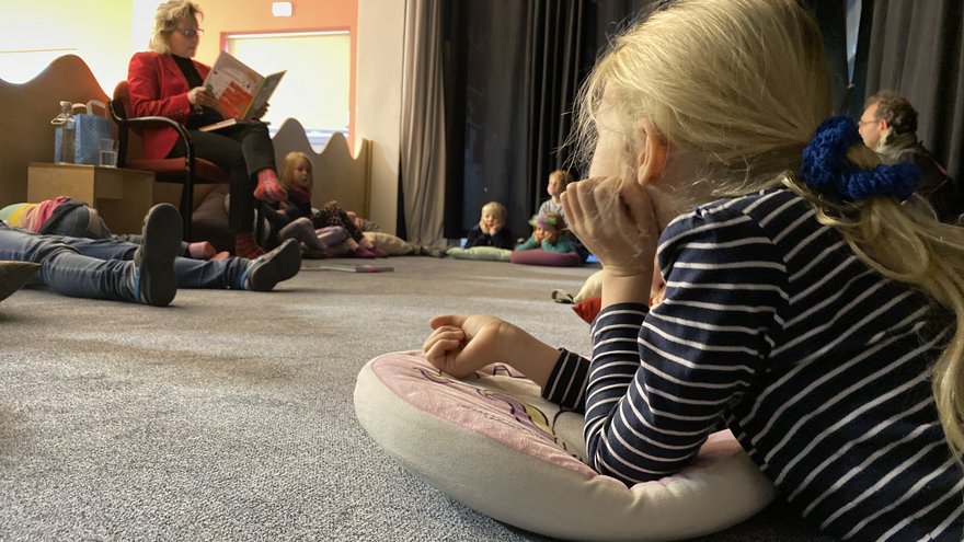 Kinder sitzen im Kreis beim Vorlesen.