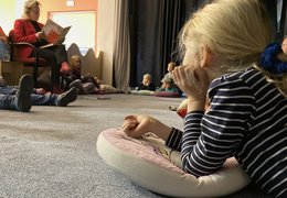 Kinder sitzen im Kreis beim Vorlesen.