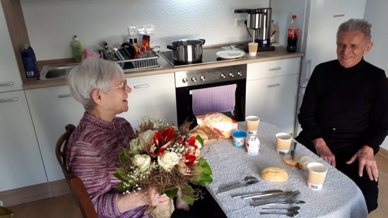 Blick in eine Wohnung: Zwei Personen sitzen am Tisch