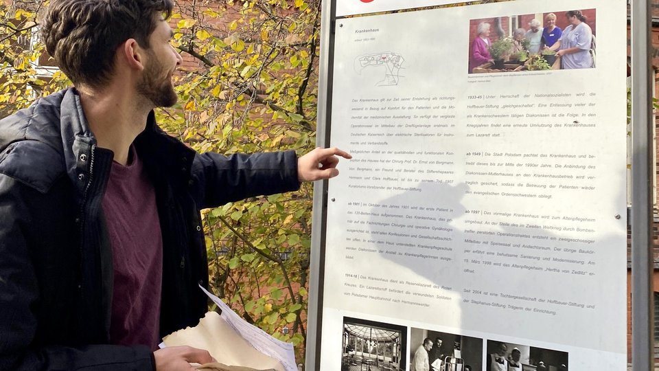 Einrichtungsleiter Matthäus Mrosek von Glischinski  steht vor einer Schrifttafel