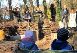 Die Kinder sitzen auf dem Waldsofa und schauen beim Theaterstück zu. 