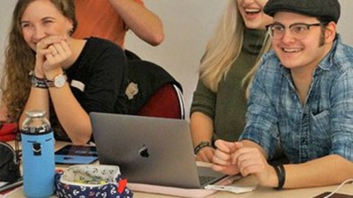 Studenten sitzen im Hörsaal am Tisch vorm Laptop