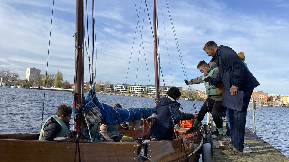Ein Lehrer hilft einem Schüler ins Boot