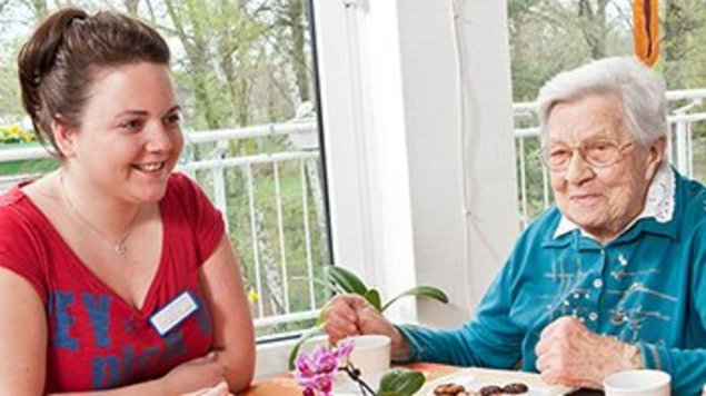 Menschen sitzen bei Kaffee und Kuchen zusammen