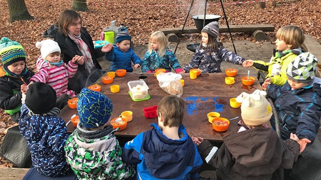 Kinder sitzen und essen an einem Tisch im Freien