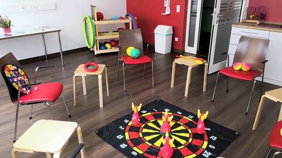 Ein Kreis aus Stühlen mit einem Spiel in der Mitte.