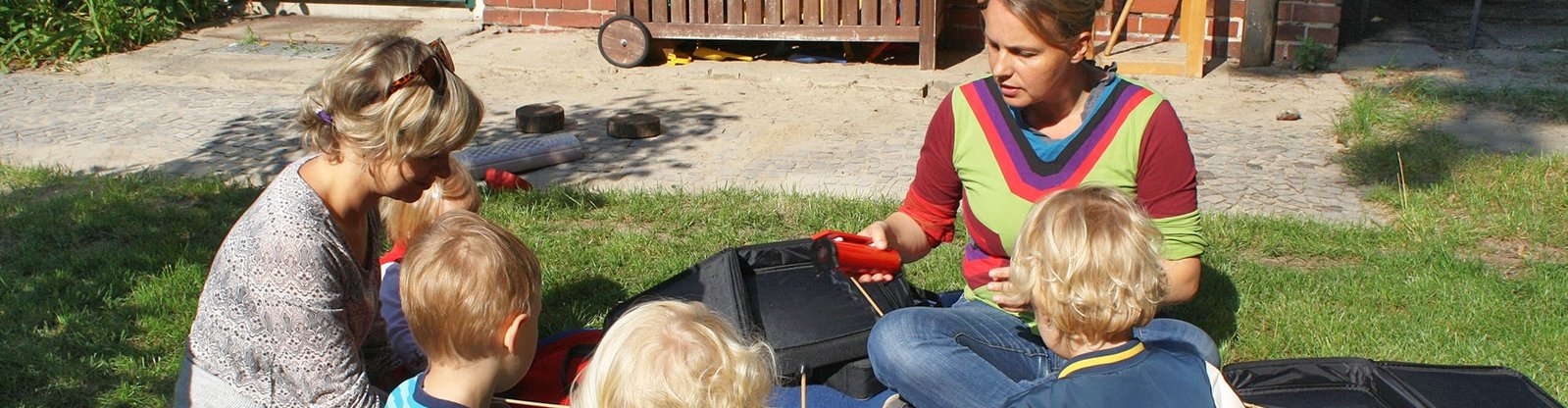 Kinder und Erzieherinnen beim Musizieren, auf der Wiese