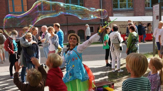 Eine Clownin macht Seifenblasen auf dem Inselfest