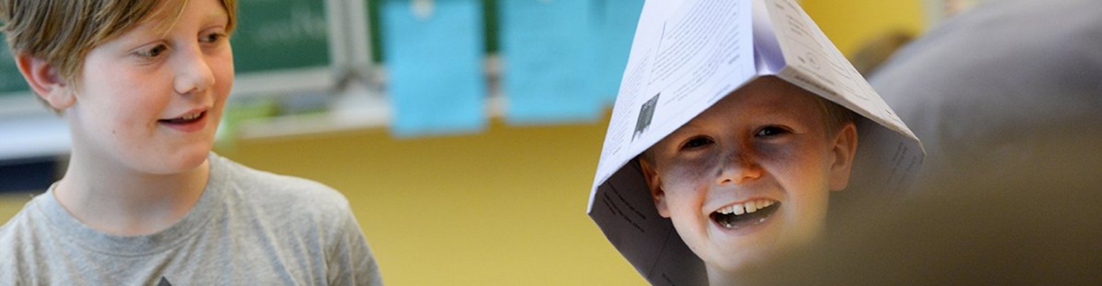 Kinder im Klassenzimmer mit Papierhüten