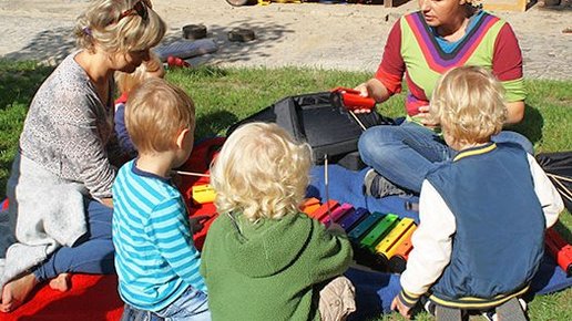 Kinder und Erzieherinnen beim Musizieren, auf der Wiese